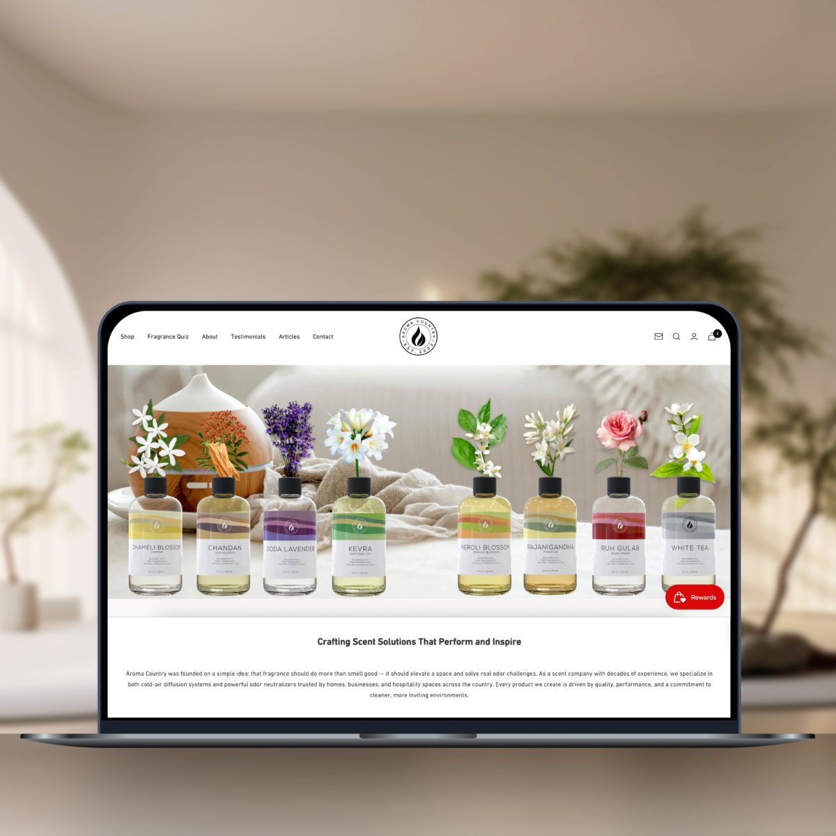 Laptop displaying Aroma Country's homepage featuring a row of diffuser oils with floral scents.
