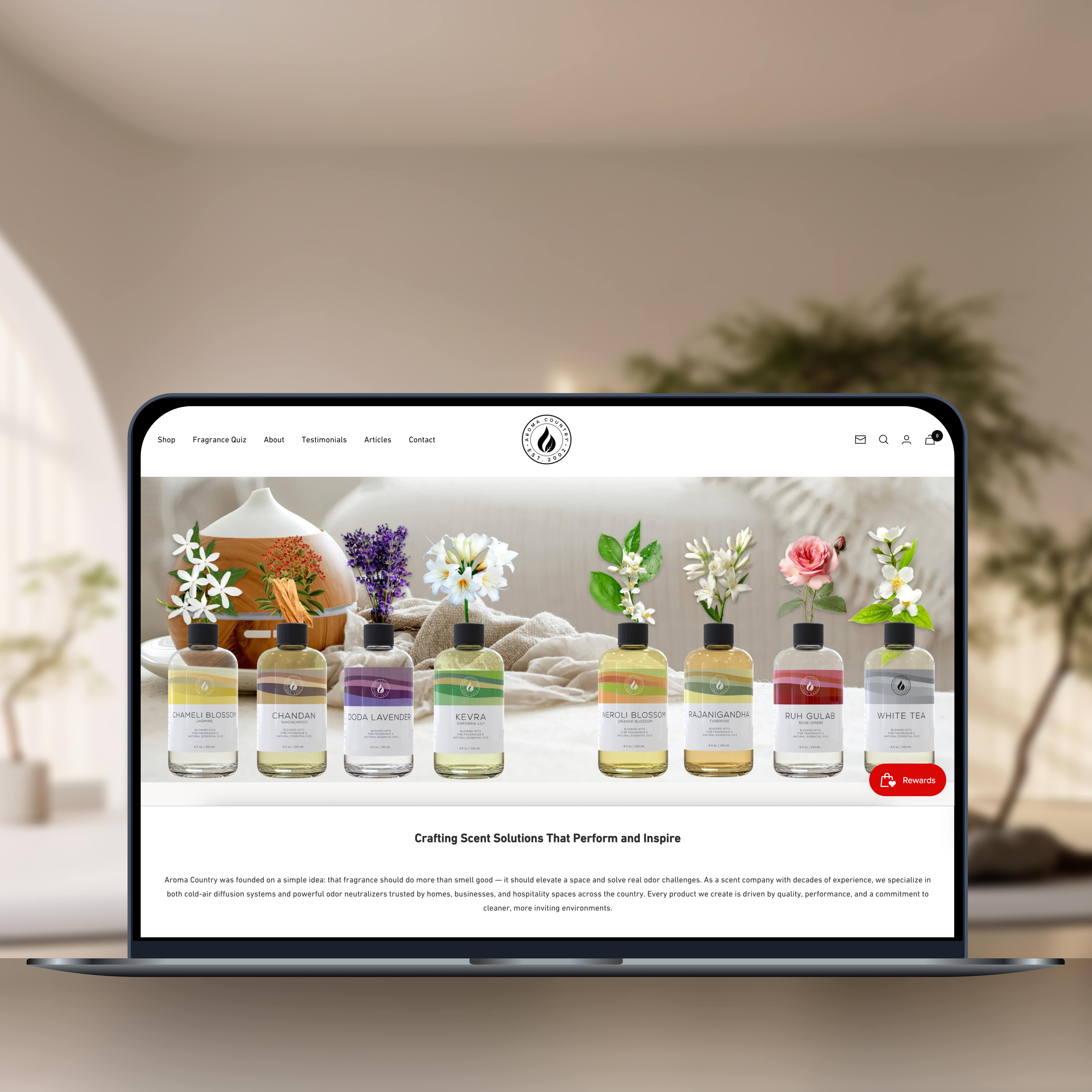 Laptop displaying Aroma Country's homepage featuring a row of diffuser oils with floral scents.