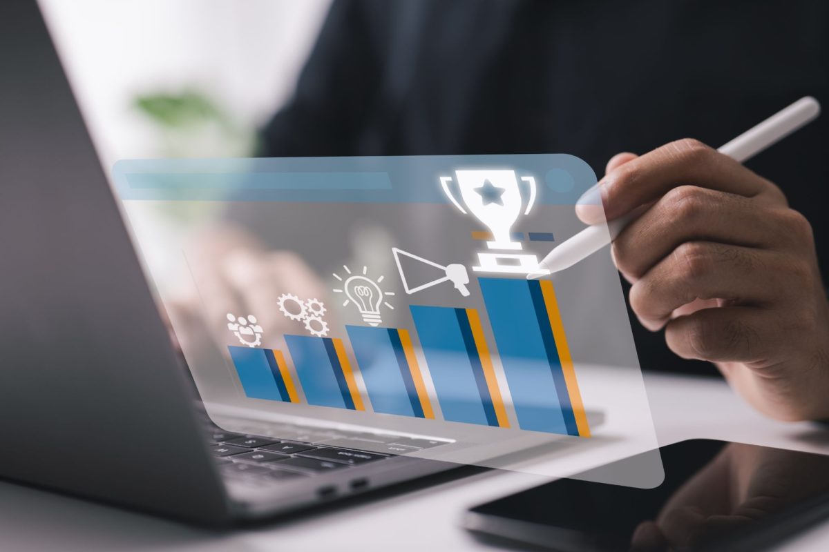 image | Digilite | Web Design Company in Glendale CA A close-up of a person using a laptop with a digital holographic interface overlay showing a rising bar chart that culminates in a trophy icon.